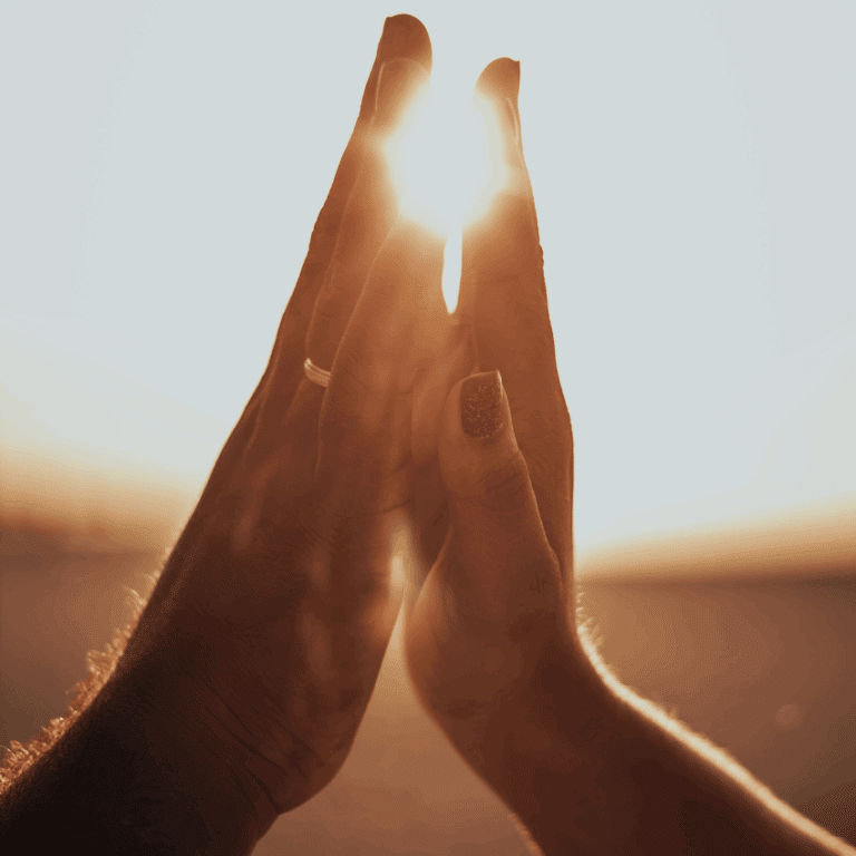 two hands are held up, almost touching. A bright light appears behind the hands, as if they are destined to soon touch.