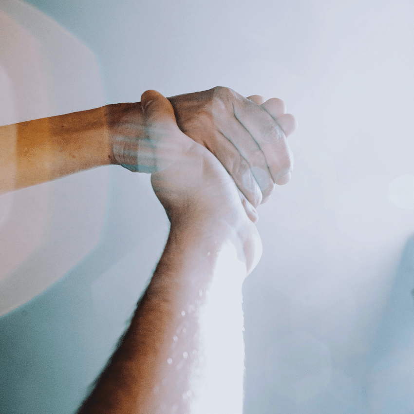 Two hands are shown holding with light reflections, representing the vibrations of the Law of Attraction.