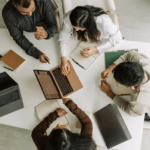 A circle of office workers around a laptop represents using numerology for career advice.