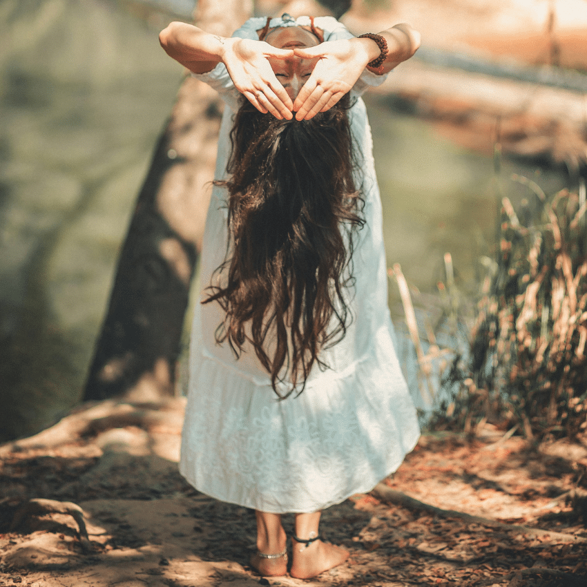 A woman bends backwards with her hands in a triangle shape. to represent Mercury's direction going direct instead of retrograde.