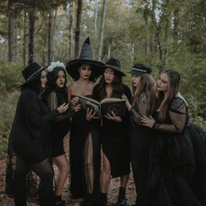A group of women who are dressed as witches surround books they are holding.