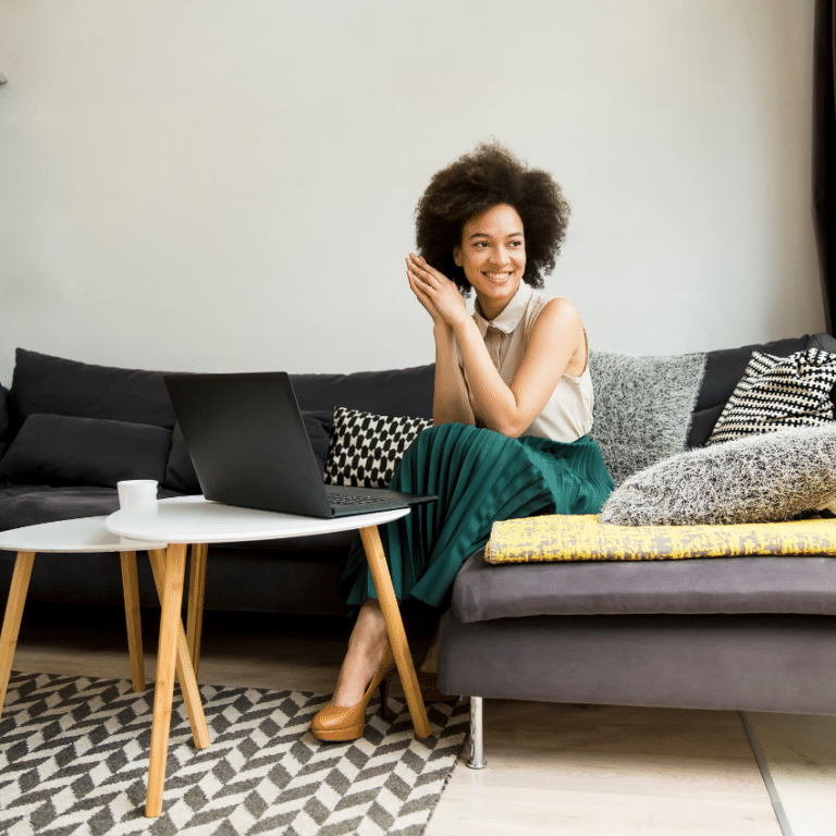 fashionable woman in a green skirt sitting on a modern grey couch smiling