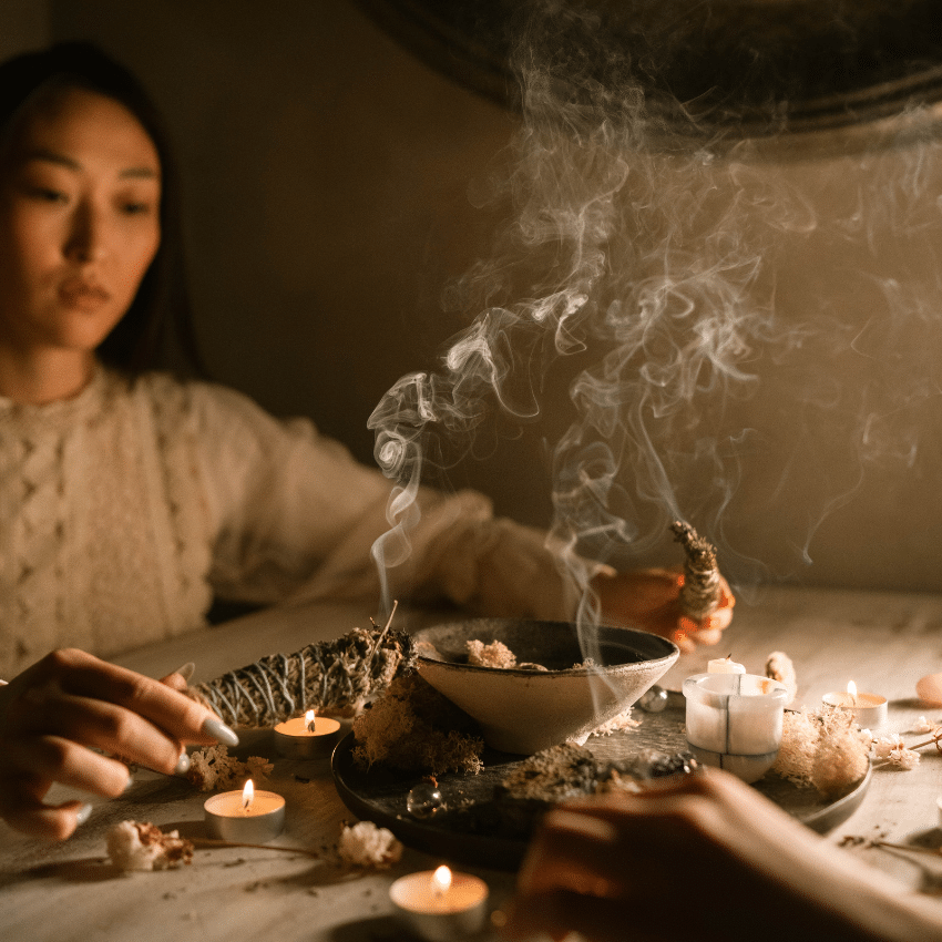 woman sitting at a table burning incense