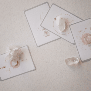 four tarot cards spread out on a white table with crystals