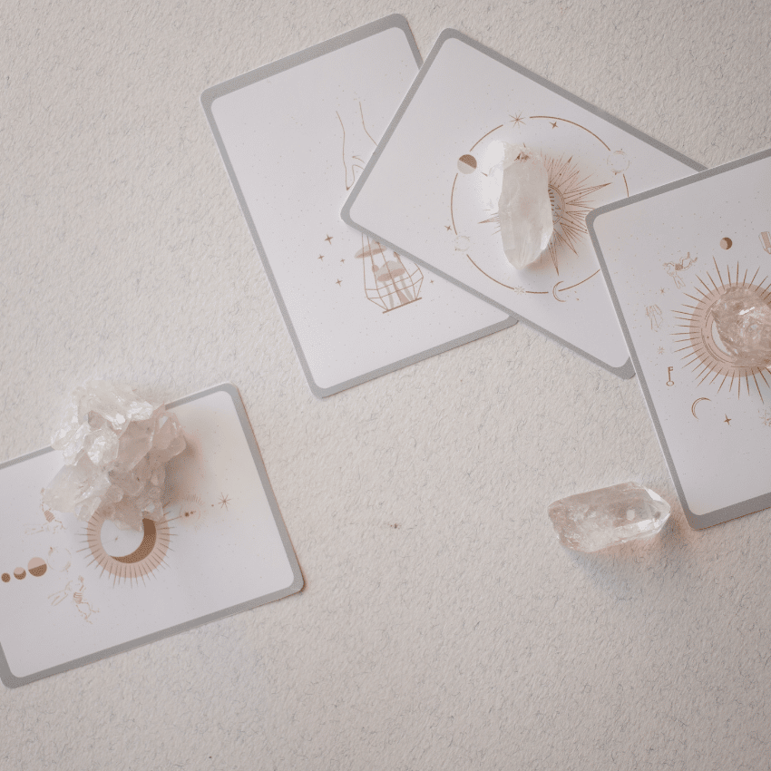 four tarot cards spread out on a white table with crystals