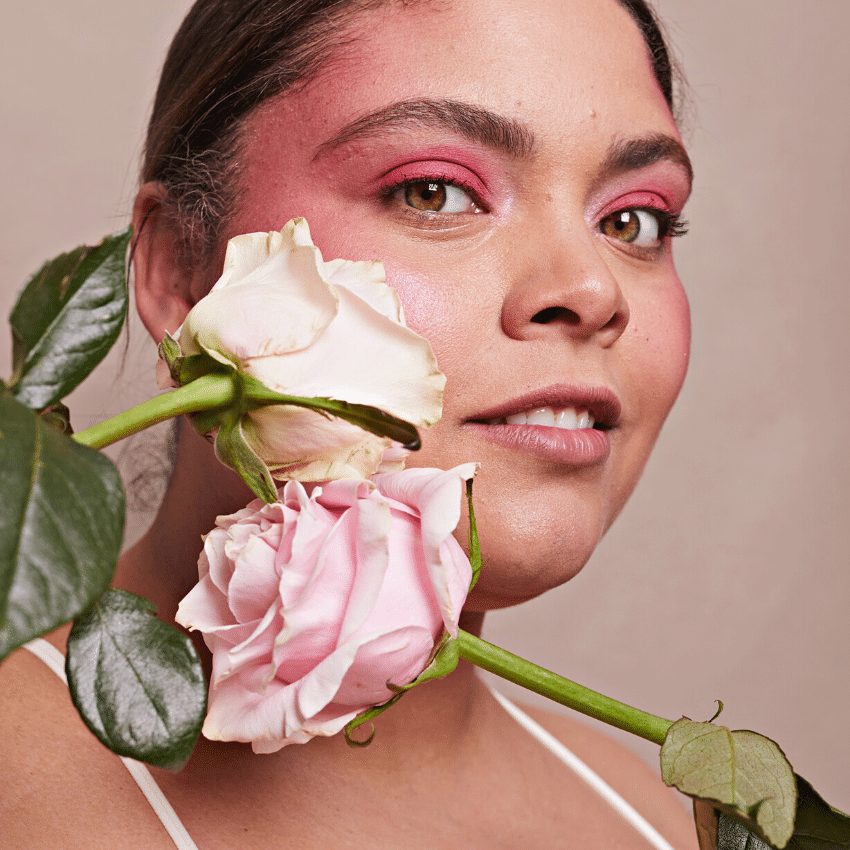 woman with red eye shadow holding up pink and white roses