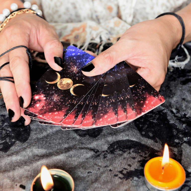 pair of hands holding out an array of tarot cards covered in moon symbols