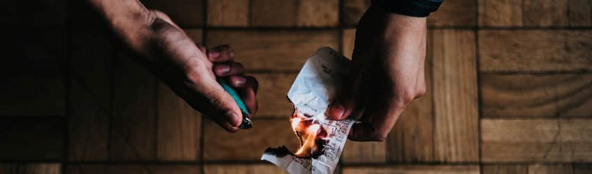 A man burns a piece of paper with a lighter to release the negative energy.