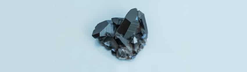 A black hematite crystal on a blue background.
