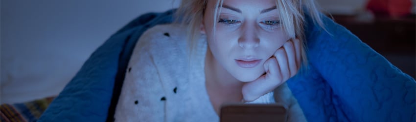 A woman is texting in bed.