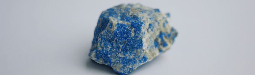 A raw chunk of Lapis Lazuli on a grey background.