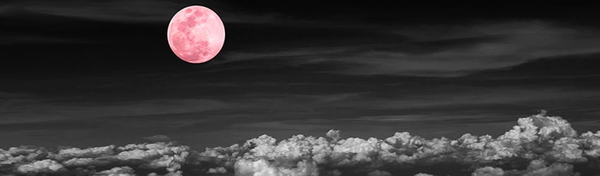 A pink moon hovers in the sky in a black background.