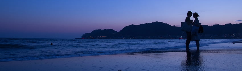 Two lovers kissing under the Moon while standing in the ocean.