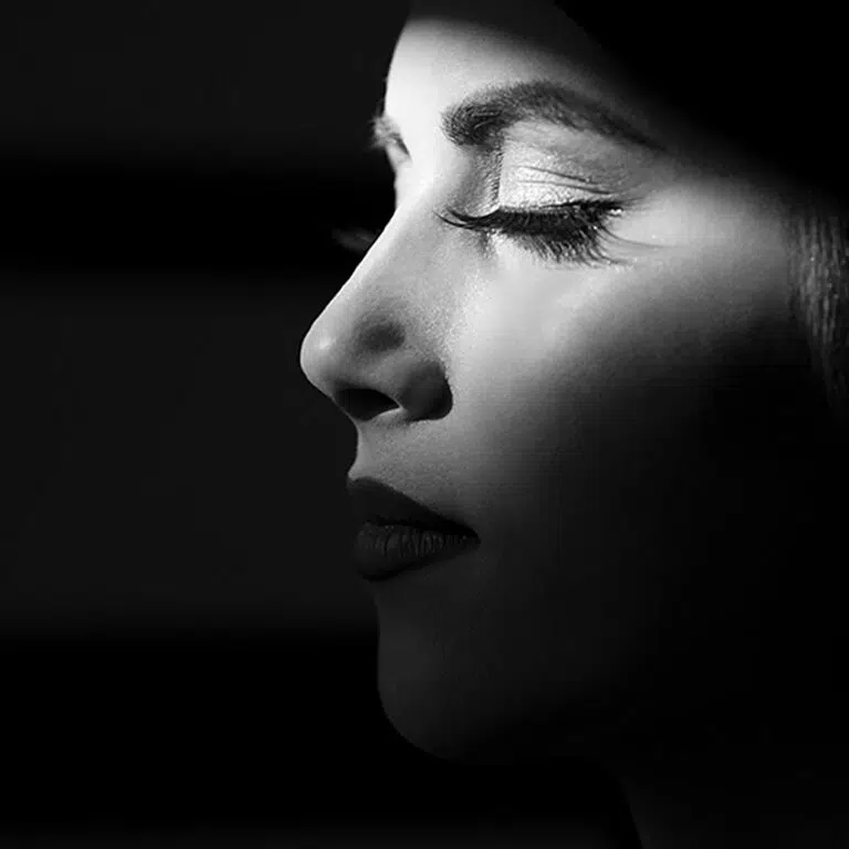a darkly shadowed image of the profile of a woman with her eyes closed.