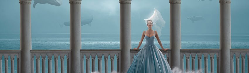 A woman wearing a veil and a formal blue gown stands with her back towards the ocean, leaning against a white railing. It appears as if there are whales in the air behind her.