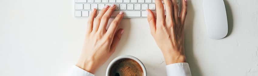 hands on keyboard with coffee cup