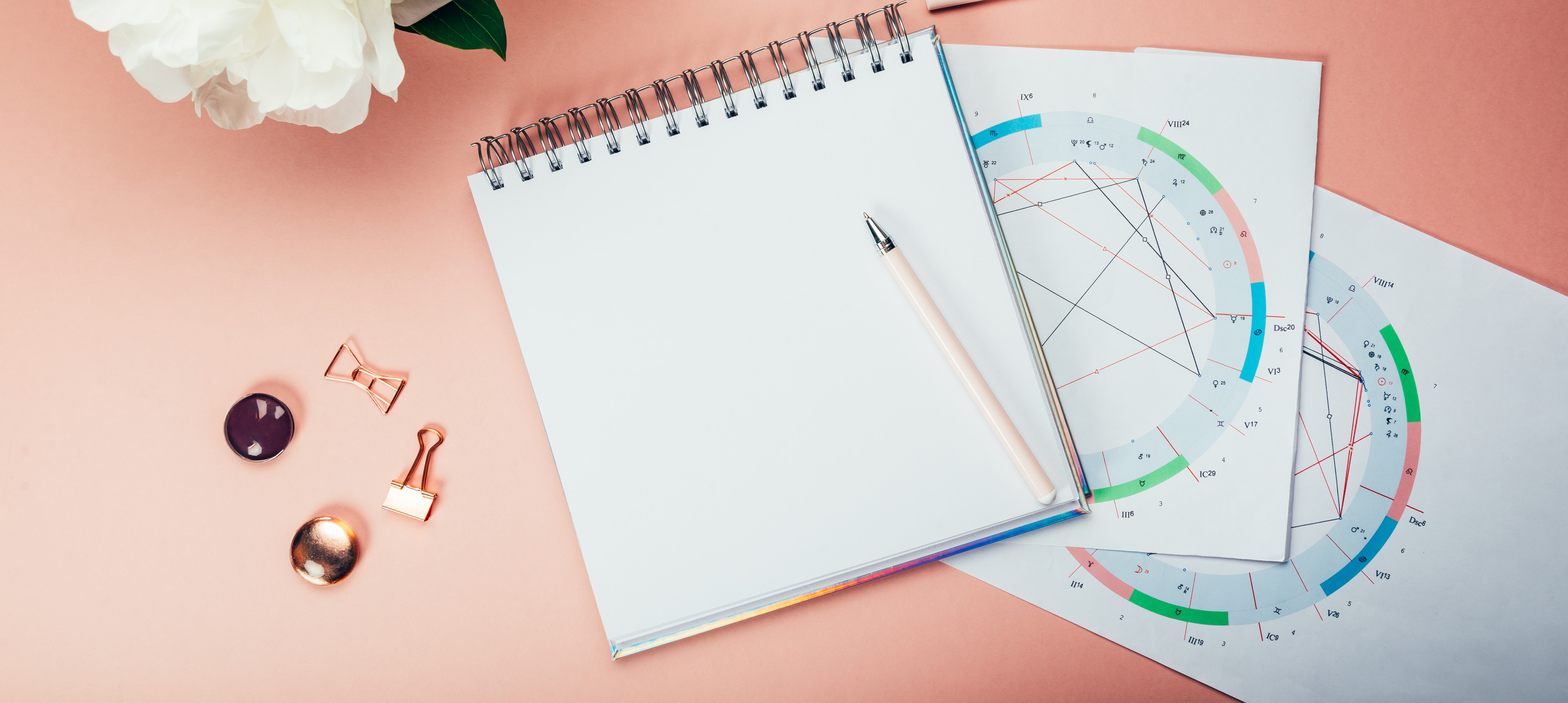 A birth chart on a table with a pen and paper pad.