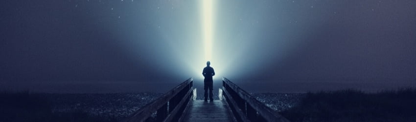 A figure stands against the night sky illuminated by a single strand of light.