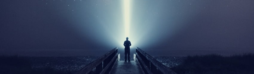 A figure stands against the night sky illuminated by a single strand of light.
