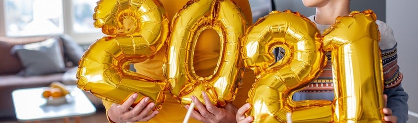 A mother and son hold gold foil balloons that spell out 2021.