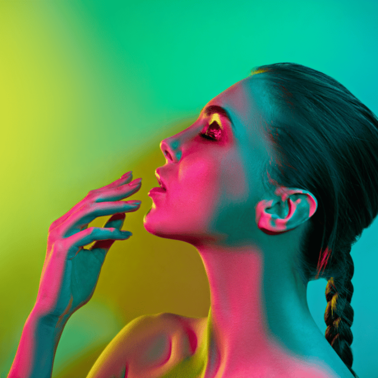 side profile of a woman with green and pink lights illuminating the side of her face