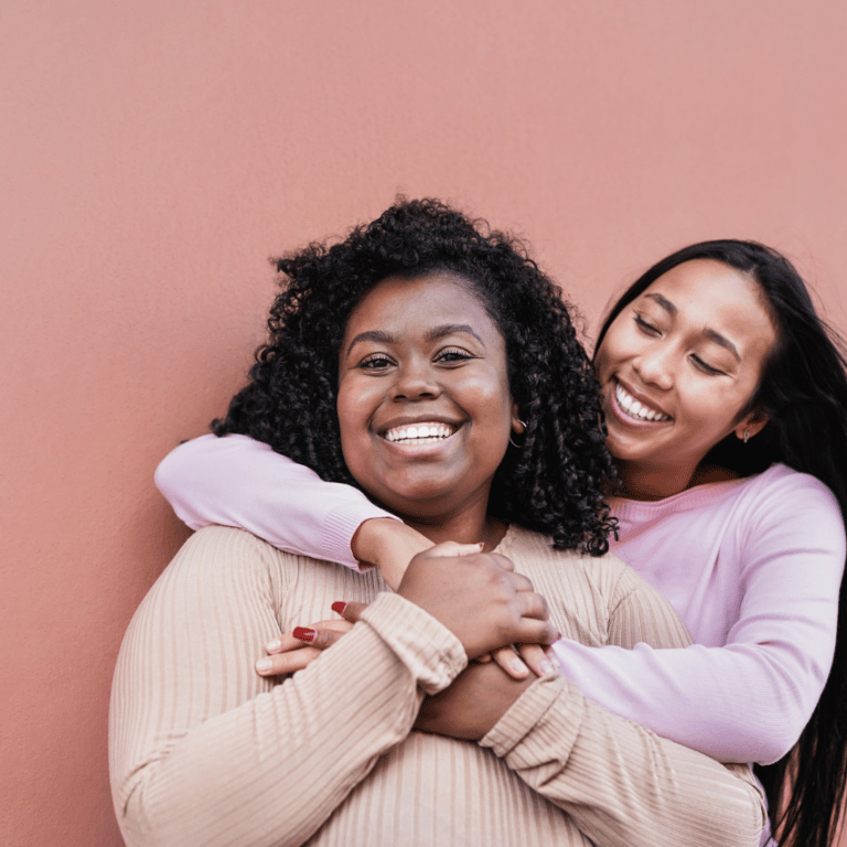 two woman embracing each other and smiling