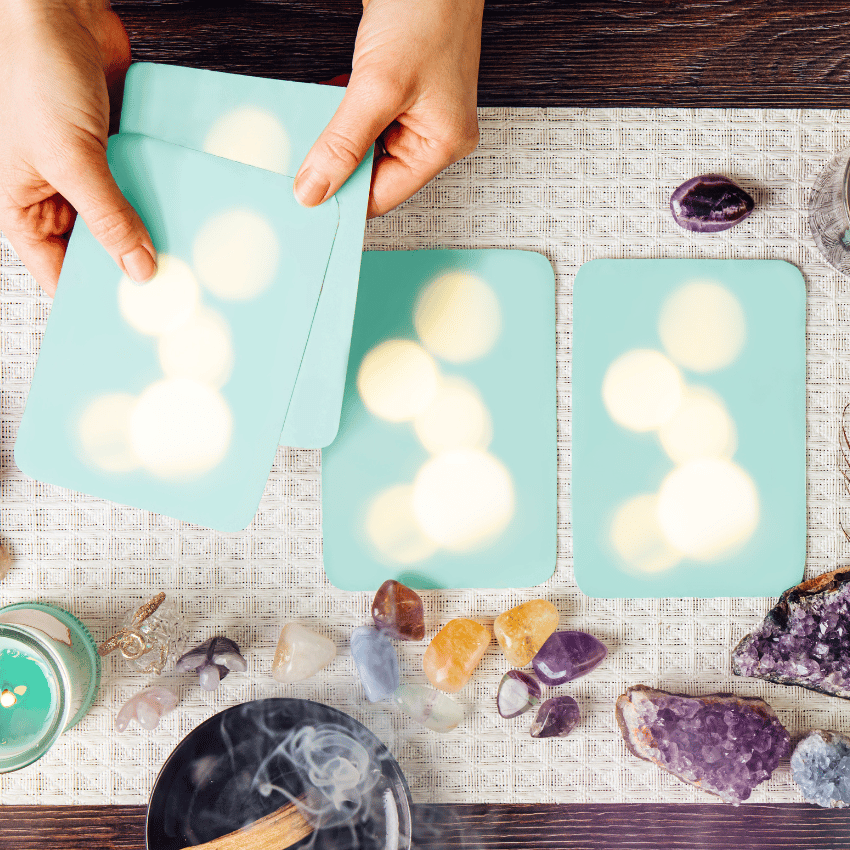 pair of hands holding out a pair of blue angel cards over a table with crystals and candles