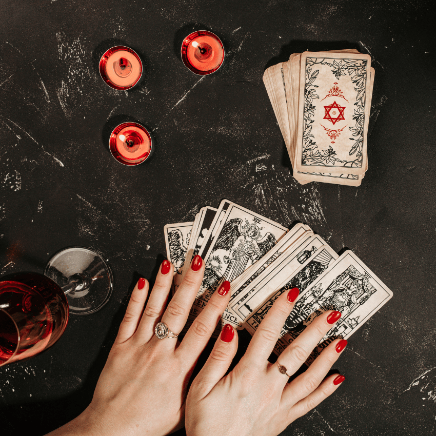 hands outstretched on a black table with tarot cards