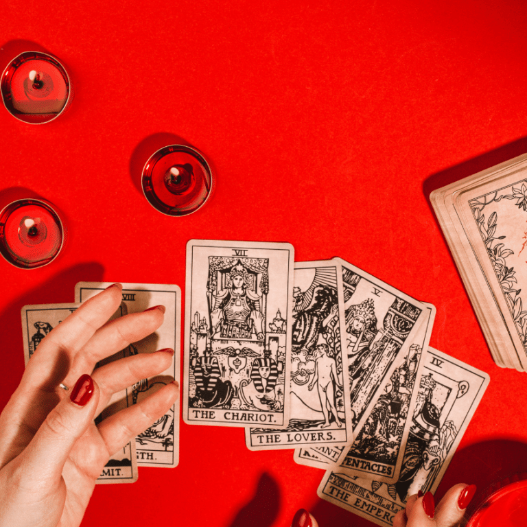hand outstretched over an array of tarot cards spread out on a red table