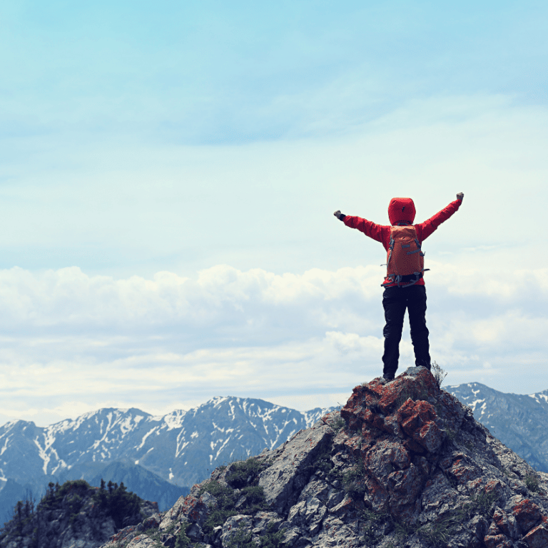 person standing on a mountain top with arms outstretched