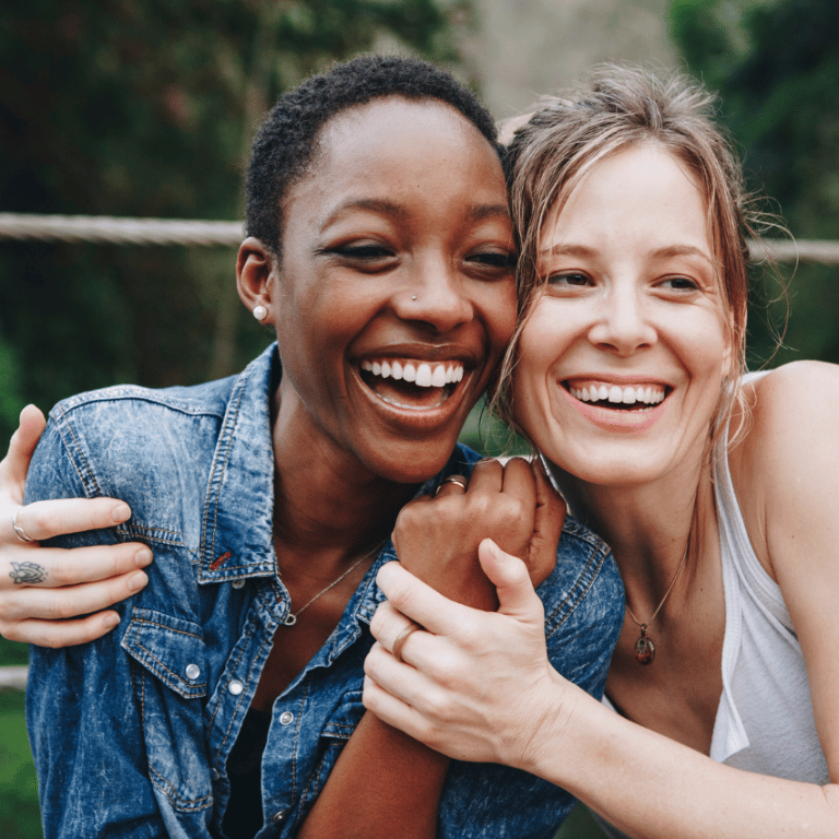 two women hugging each other and smiling