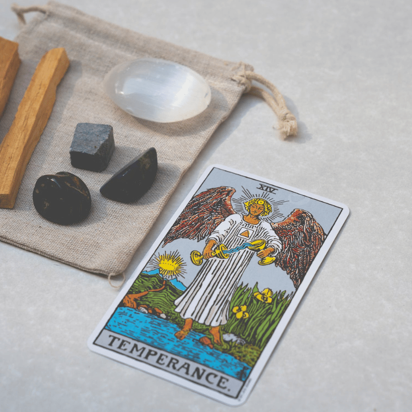 temperance tarot card on a table next to crystals and sage