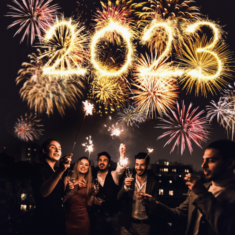 group of people celebrating new years' eve with sparklers and fireworks in the sky spelling out 2023