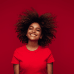 woman smiling in joy wearing a read t-shirt against a red backdrop