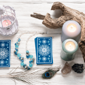 pile of blue tarot cards on a white table covered in candles, crystals, and wood