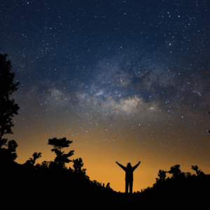 man outside with his arms outstretched to a starry blue and yellow sky