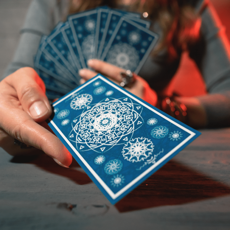 outstretched hand holding a blue tarot card