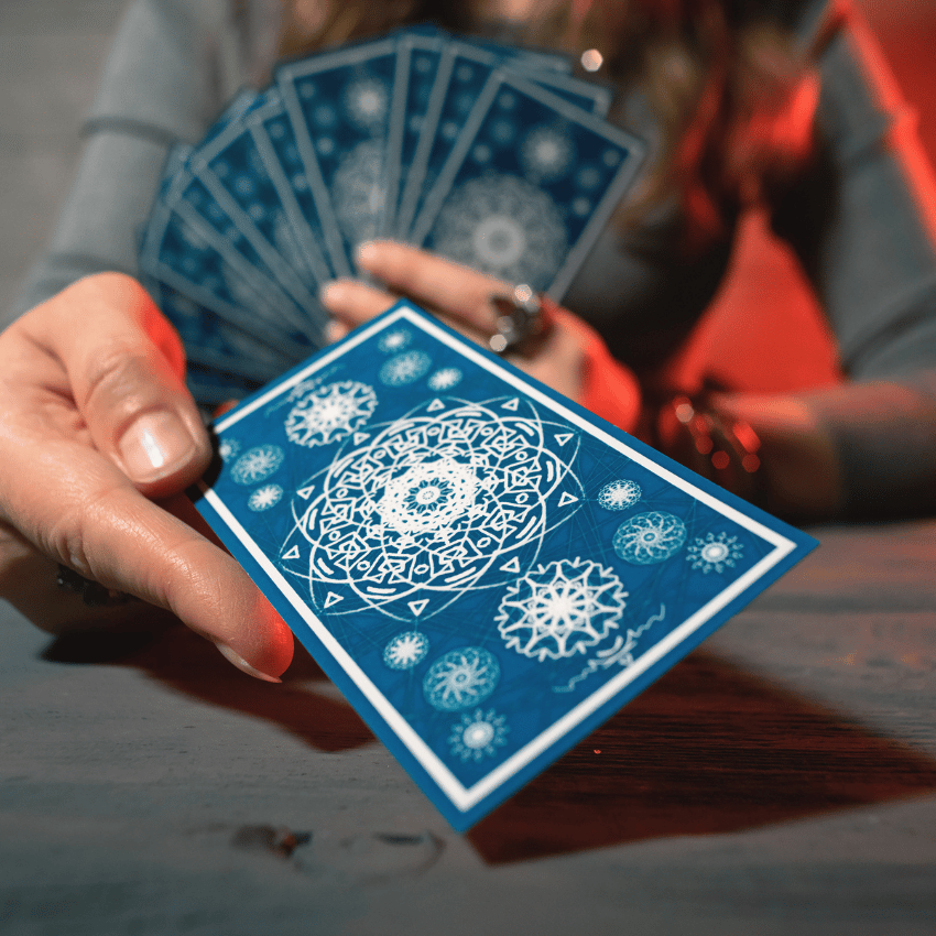 outstretched hand holding a blue tarot card