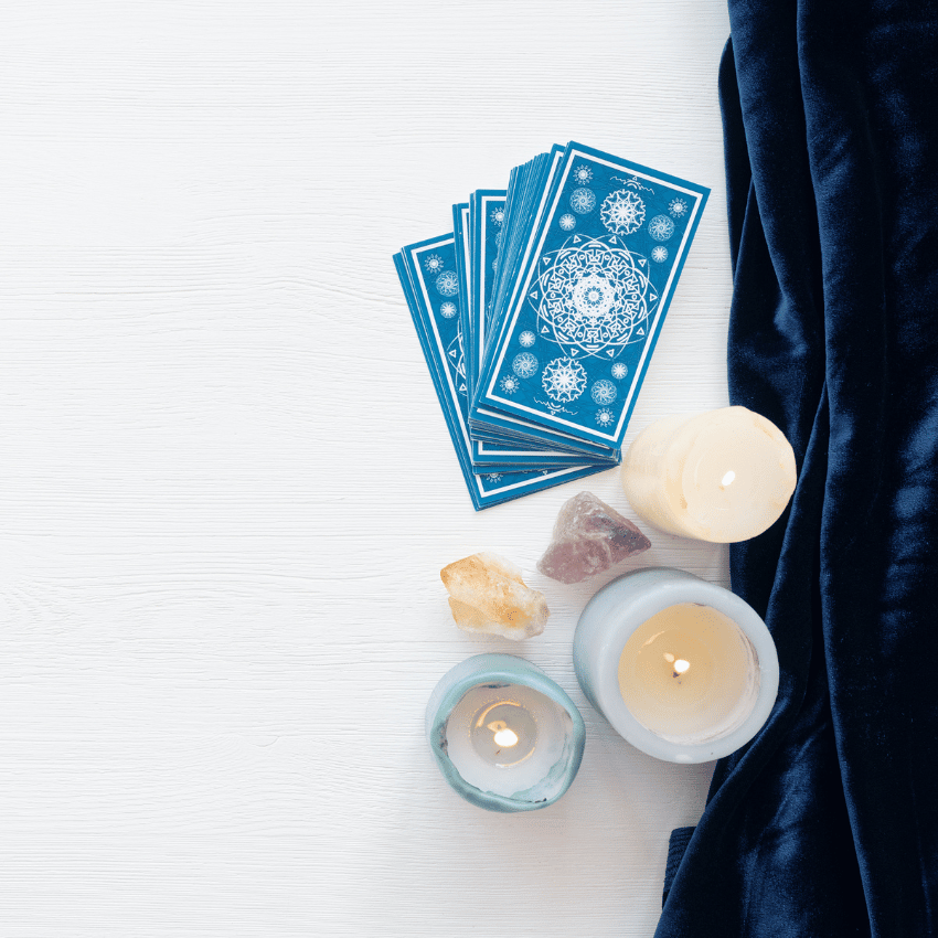 blue tarot cards on a white table surrounded by candles and crystals