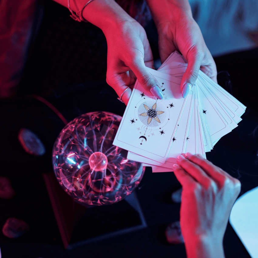 pair of hands holding out white tarot cards over a crystal ball