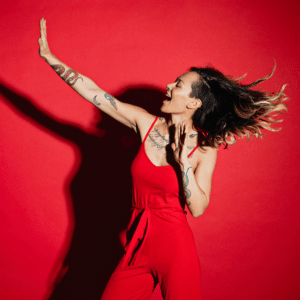 woman in a red jumper against a red background jumping up