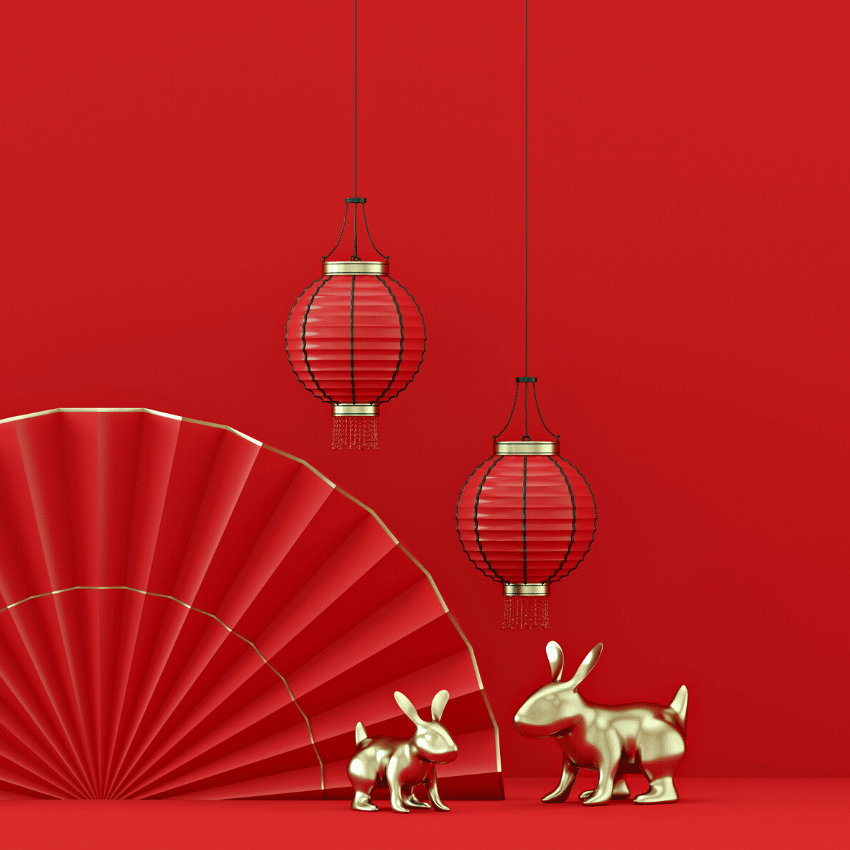 two gold rabbit statues against a red backdrop