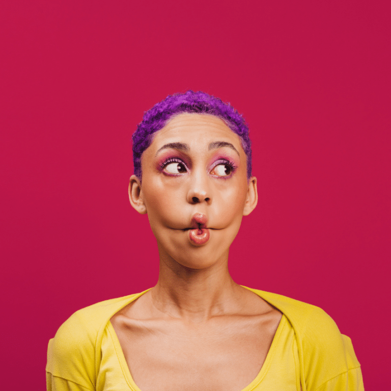 woman with short purple hair and a yellow shirt making fish lips