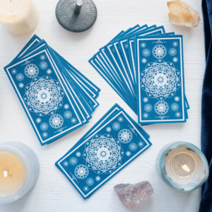 three stacks of blue tarot cards on a white table surrounded by candles and crystals