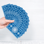 a hand holding out a spread of blue tarot cards
