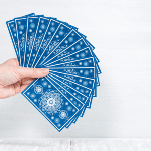 a hand holding out a spread of blue tarot cards