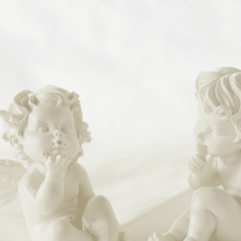 two white baby angel statues blowing kisses at each other