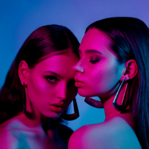 two twin women with big hoop earrings and long straight hair in blue and pink lighting