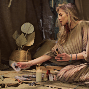 blonde woman reading tarot cards on a carpet adorned with crystals and candles while burning sage