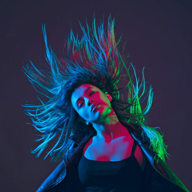 woman with long hair shaking her head in a dim-light setting